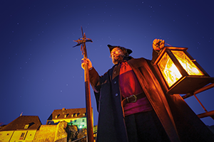 Titelbild Bereich 'Was Ihr wissen solltet', Chnutz als Nachtwächter mit Hellebarde und Laterne von schräg unten photographiert